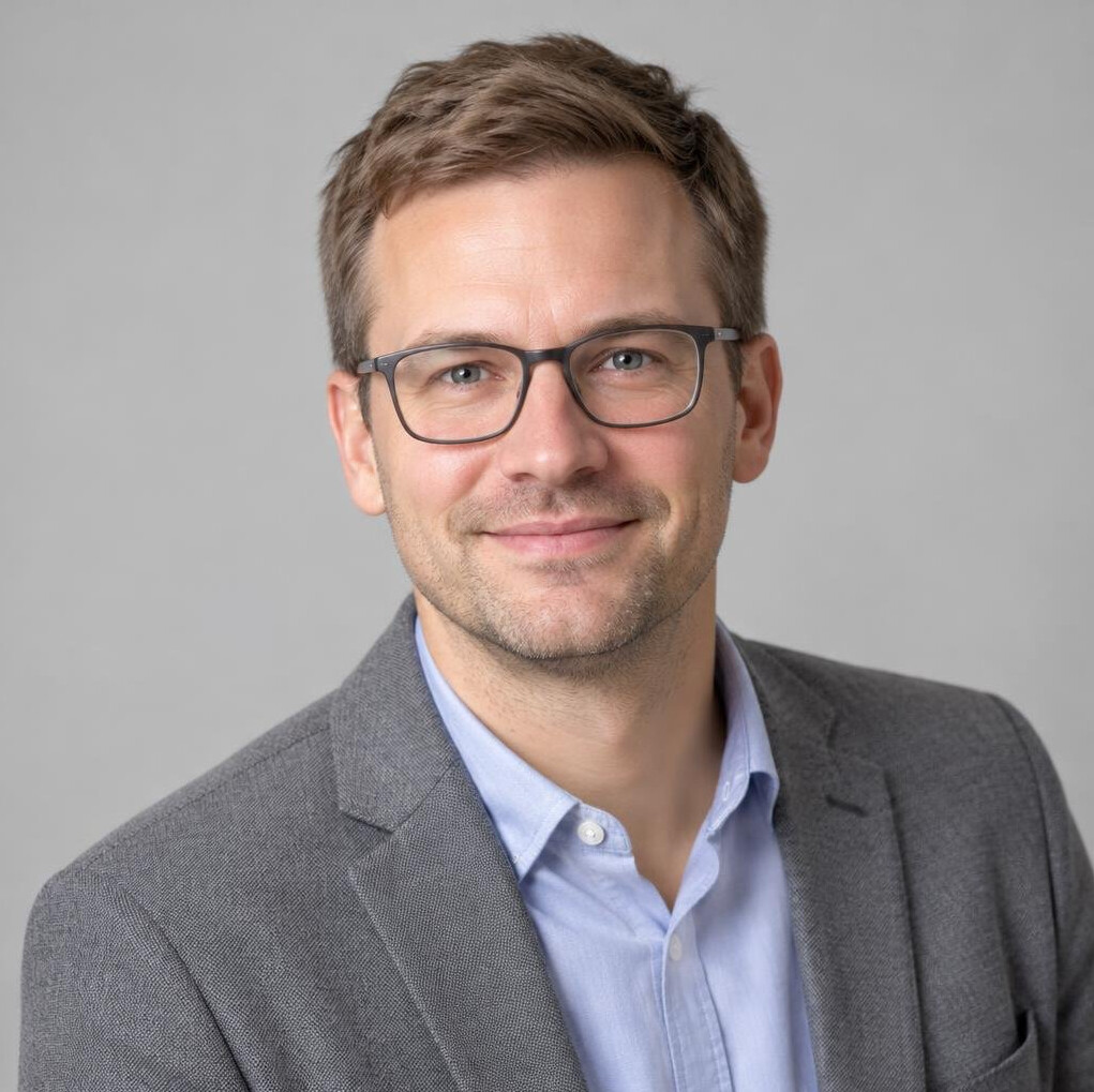 Portrait of a man in his thirties with glasses and a casual blazer
